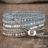 Multistrand beaded bracelet with metal clasp on a wooden surface, labeled 'Free Spirit Shop'.