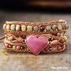 Multistrand bracelet with heart-shaped pink stone on a wooden surface, 'Free Spirit Shop' branding visible.