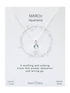 Necklace with an aquamarine stone on a branded card, featuring text about the gemstone.