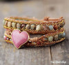 Multistrand bracelet with heart charm on a wooden surface, featuring Free Spirit Shop branding.